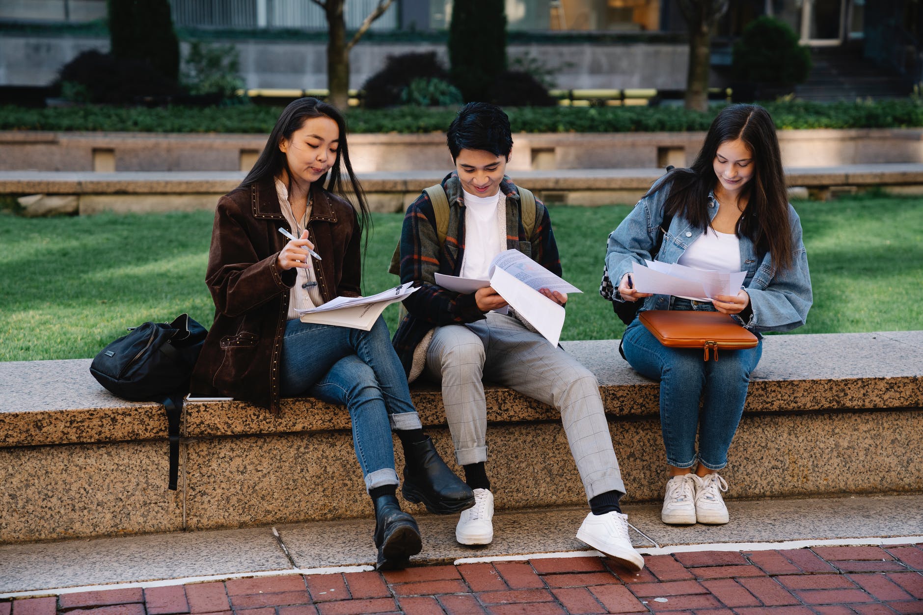 group of students sitting on a concrete bench